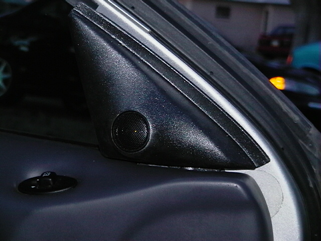 Close-up of a car's A-pillar trim with a speaker grille and a door lock switch