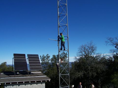 1998 Ford Ranger - Workers are on a tall tower, with solar panels installed on a nearby roof.