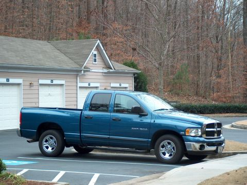 2004 Dodge 1500 - A blue Dodge Ram 1500 pickup truck is parked in a driveway next to a residential garage.