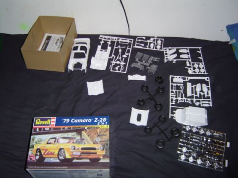 1979 Ford Bronco - Unassembled model car kit parts are spread across a black surface, with the box for a '79 Camaro Z-28 visible.