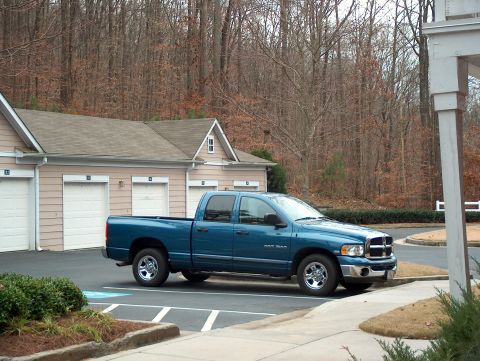 2004 Dodge 1500 - A blue 2004 Dodge 1500 pickup truck is parked in a lot near a residential building.