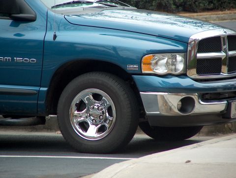 2004 Dodge 1500 - A teal Dodge Ram 1500 truck is shown from the front quarter angle, highlighting its grille and front wheel.