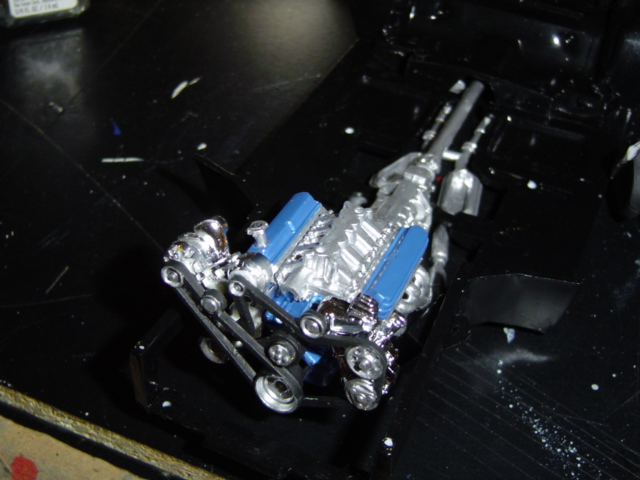 Model engine with blue valve covers and chrome details on a black surface
