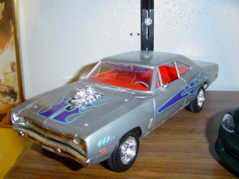 1979 Ford Bronco - A silver model car with flame decals and a prominent engine scoop sits on a shelf next to another vehicle.