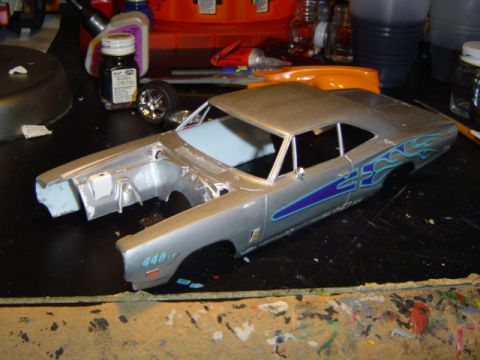 1979 Ford Bronco - A silver model car with blue flame decals and "440" visible on the fender sits on a workbench with hobby supplies.