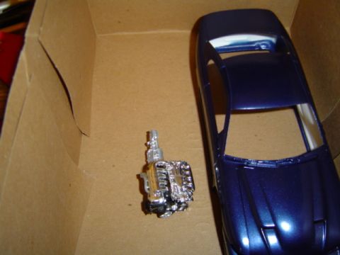1979 Ford Bronco - A model car engine and blue body are shown inside a cardboard box.