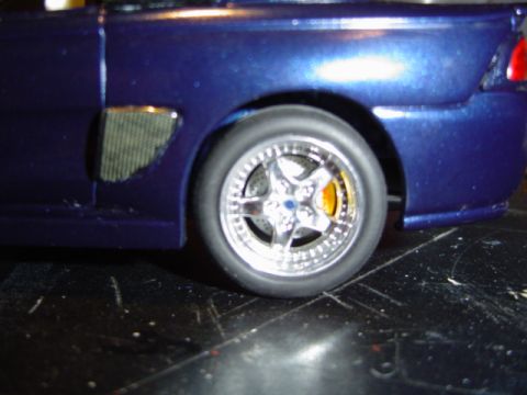 1979 Ford Bronco - Close-up of a model car's rear wheel and fender, showing custom rims and a textured vent detail.