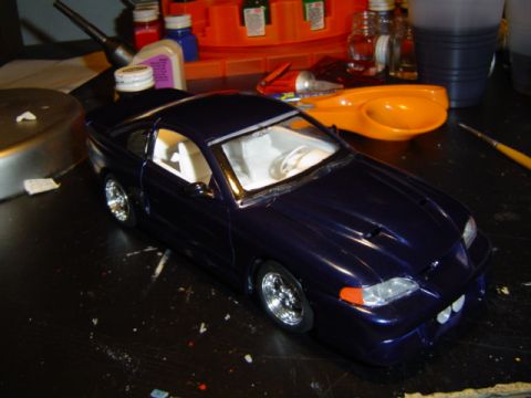 1979 Ford Bronco - Model car on a workbench with hobby supplies in the background. Supermotors.net logo is present.
