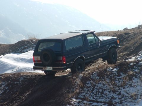 1991 Ford Bronco - This 1991 Ford Bronco is navigating a challenging, snowy incline on a dirt trail.