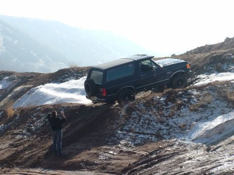 1991 Ford Bronco - A black 1991 Ford Bronco navigates a steep, muddy, and snowy incline.