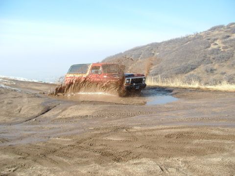 1991 Ford Bronco - Off-road vehicles churn up mud while navigating a difficult terrain.