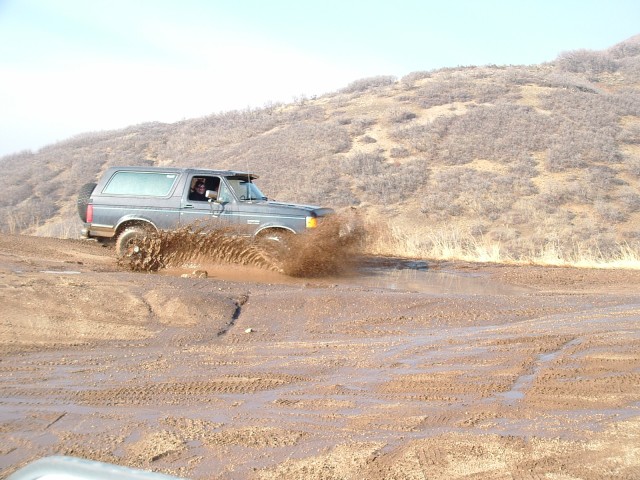 Gray 1991 Ford Bronco driving through mud, splashing water