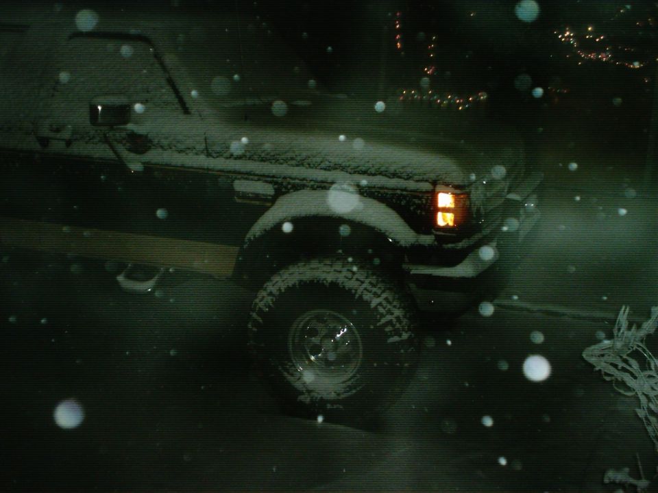 Ford F-Series truck in snow, headlights on