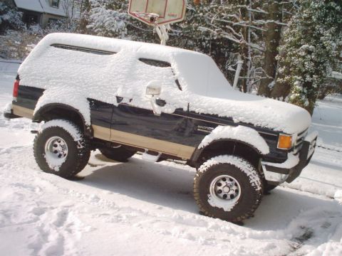 1989 Ford Bronco - A Ford Bronco sits covered in snow, with a basketball hoop visible in the background.