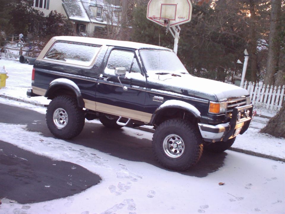 1989 Ford Bronco parked on a snowy street with a basketball hoop in the background