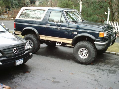 1989 Ford Bronco - This 1989 Ford Bronco features a two-tone paint scheme and is parked next to a Mercedes-Benz.