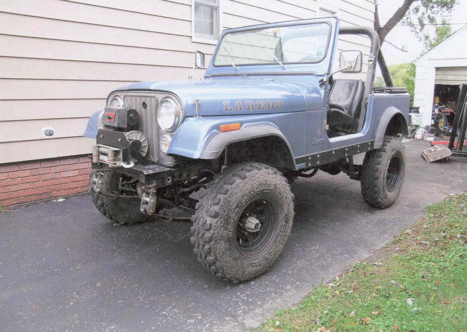 Blue Jeep CJ-7 Laredo with winch and aftermarket fender flares parked on driveway