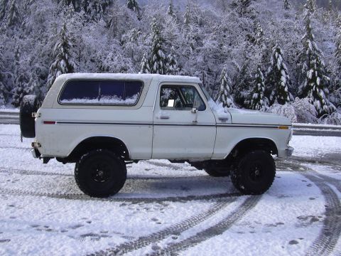 1978 Ford Bronco - A white 1978 Ford Bronco sits in a snowy landscape, its tires leaving tracks on the ground.