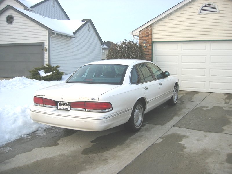 White 1997 Ford Crown Victoria parked in a driveway with snow on the ground