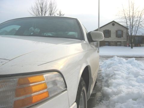 1997 Ford Crown Victoria - A white sedan is parked in front of a house with snow on the ground.