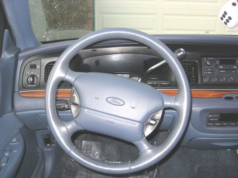 1997 Ford Crown Victoria - The interior of a Ford Crown Victoria, a steering wheel, dashboard, and a pair of dice hanging from the mirror.