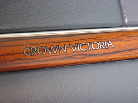 1997 Ford Crown Victoria - Close-up of the 'Crown Victoria' emblem on the interior wood trim of a vehicle.