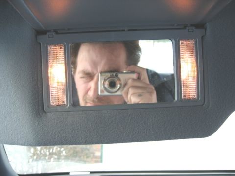 1997 Ford Crown Victoria - A person takes a selfie in the car's visor mirror, showing illuminated vanity lights.