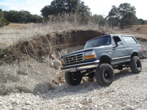 1995 Ford Bronco - This 1995 Ford Bronco is captured in a three-quarter front view while navigating a , rocky landscape.
