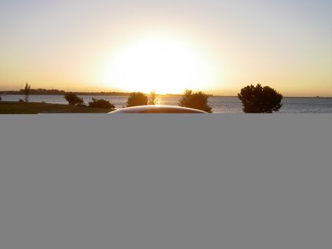 2003 Ford Taurus - A car's roof is visible in the foreground with a sunset over the water in the background.