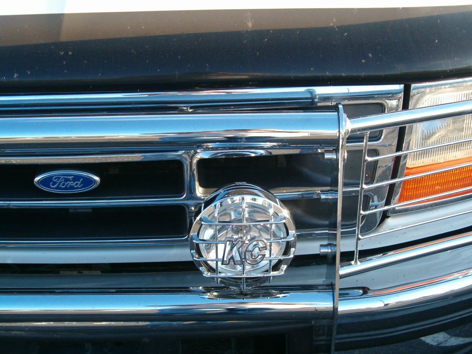 Chrome KC driving light on a tube grille guard over a black Ford grille with blue oval badge