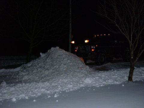 1985 Ford F-150 - A truck equipped with a snow plow is seen at night next to a large snowdrift.