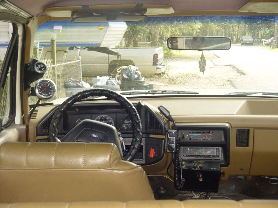 Tan interior dashboard of a Ford truck with aftermarket gauges and stereo