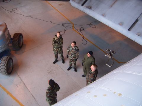 1988 Ford Bronco - Several individuals in military attire observe a large industrial machine indoors.