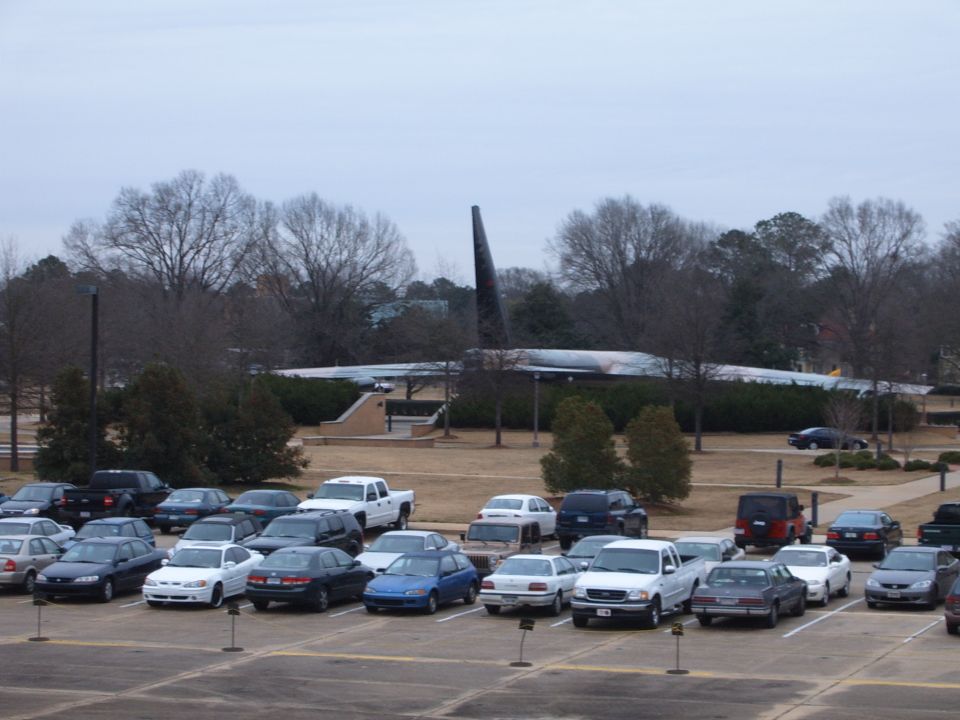 Parking lot scene with many cars and a large airplane in the background