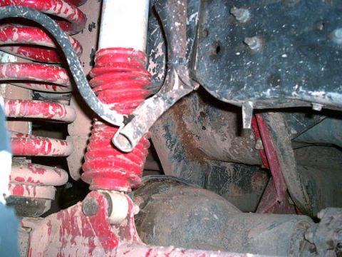 1988 Ford Bronco - This image shows the suspension system of a vehicle, including coil springs and shock absorbers, covered in dirt and mud.