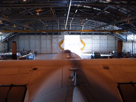 1988 Ford Bronco - Interior view of an aircraft hangar, showing a large wing in the foreground and the open bay doors in the distance. Watermark reads Supermo…