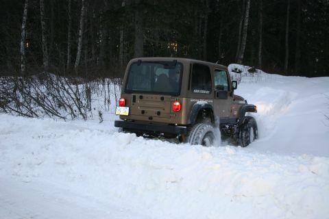 2003 Jeep TJ - This Jeep TJ is navigating a snowy trail with trees lining the path.