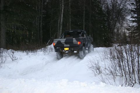 2003 Jeep TJ - A pickup truck navigates a snowy path through a wooded area.