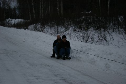 2003 Jeep TJ - Winter fun: two people ride a sled pulled by a rope up a snow-covered slope.