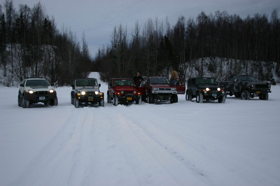 Six vehicles, including several Jeep TJs, parked in a snowy landscape