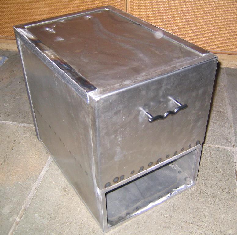 Metal box with a handle and an open drawer compartment, resting on a tiled floor