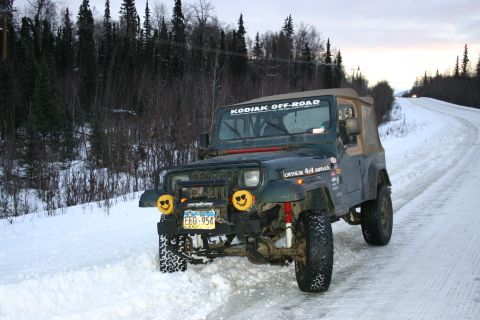 2003 Jeep TJ - A green Jeep Wrangler with "Kodiak Off-Road" text on the windshield sits on a snowy road.
