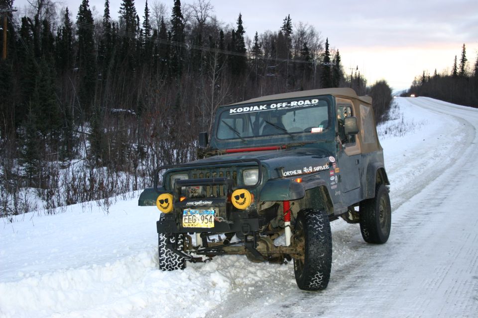 Green Jeep Wrangler with "Kodiak Off-Road" sticker on windshield, parked on a snowy road