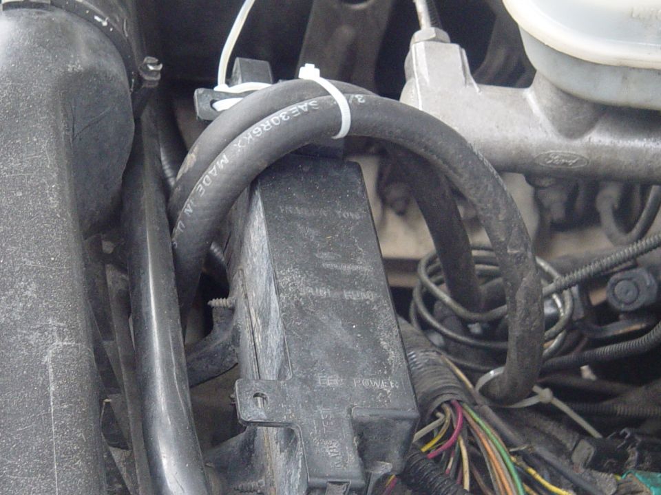 Close-up of engine bay with hoses, wiring, and a black electrical box. Text on box reads 'TRAILER TOW' and 'EE POWER'