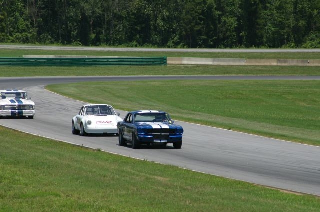 1965 Ford Mustang and two other race cars on a track