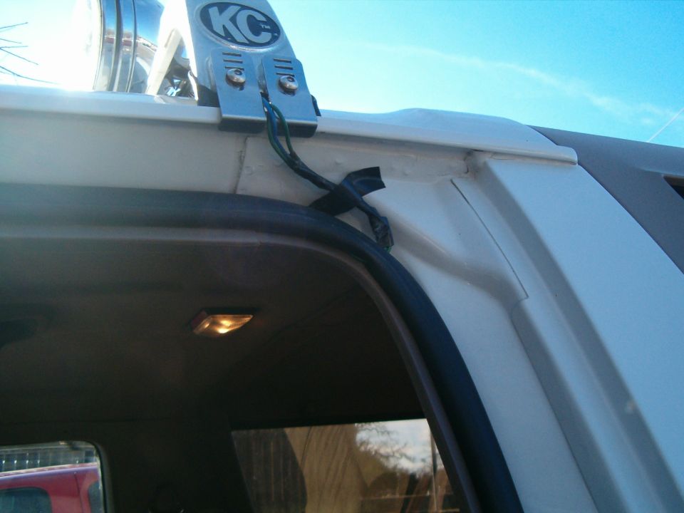 KC logo light bar mounted on white vehicle roof, wires taped