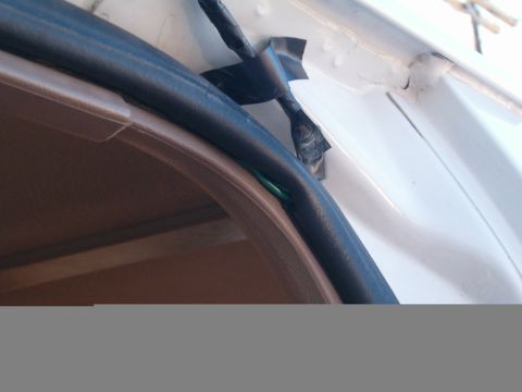 1996 Ford Bronco - Close-up of a door seal and wiring secured with tape on a white vehicle.