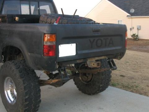 1986 Ford F-150 - The rear of a black Toyota pickup truck is shown, a spare tire and a tow hitch.