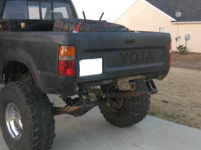 Black Toyota pickup truck's rear with a spare tire in the bed and a tow hitch