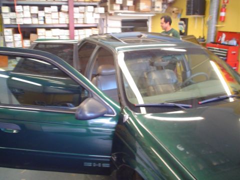 1993 Ford Taurus - A green 1993 Ford Taurus sedan is parked inside a garage with its driver's door open.